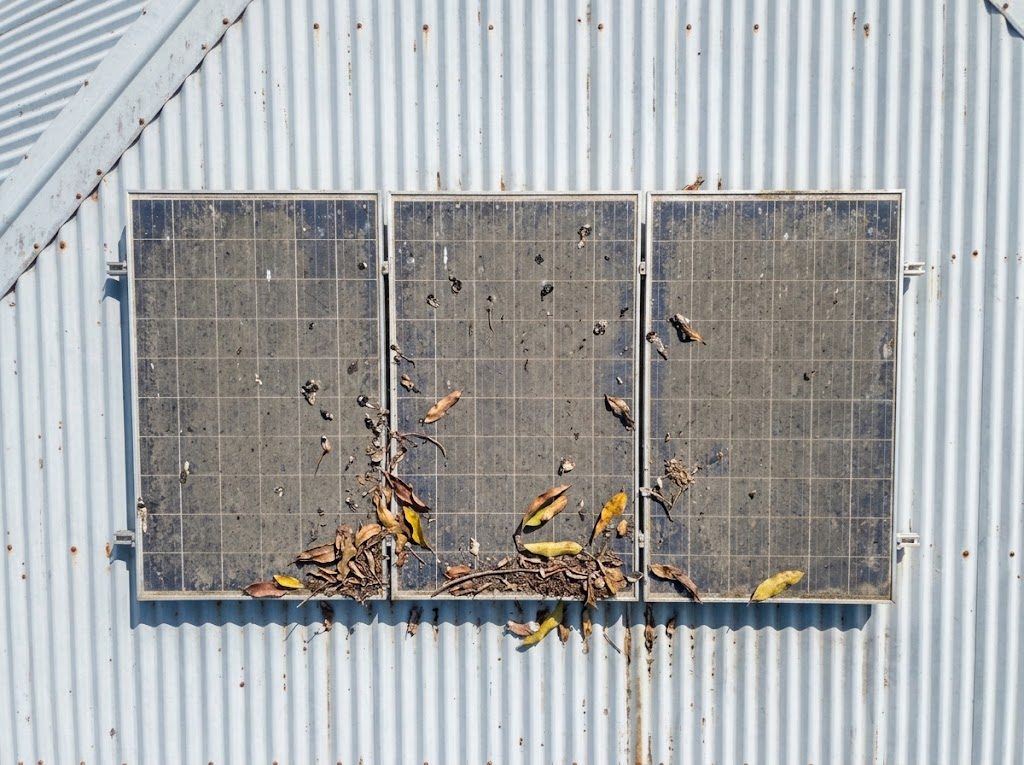 Solar panels before cleaning, covered in dust and leaves